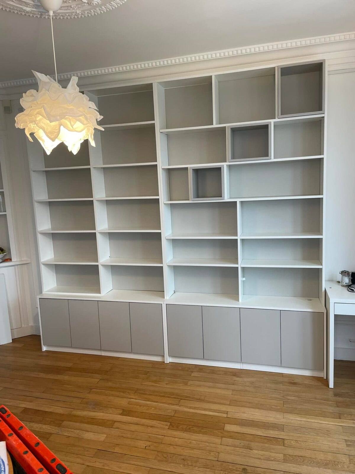 Bibliothèque blanche sur mesure à niches dans un salon à moulures