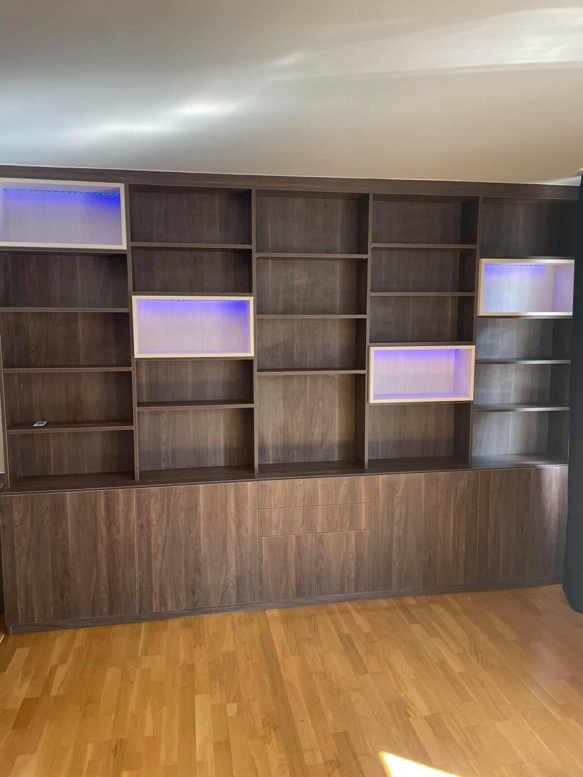 Bibliothèque en bois foncé avec niches blanches éclairées par LED