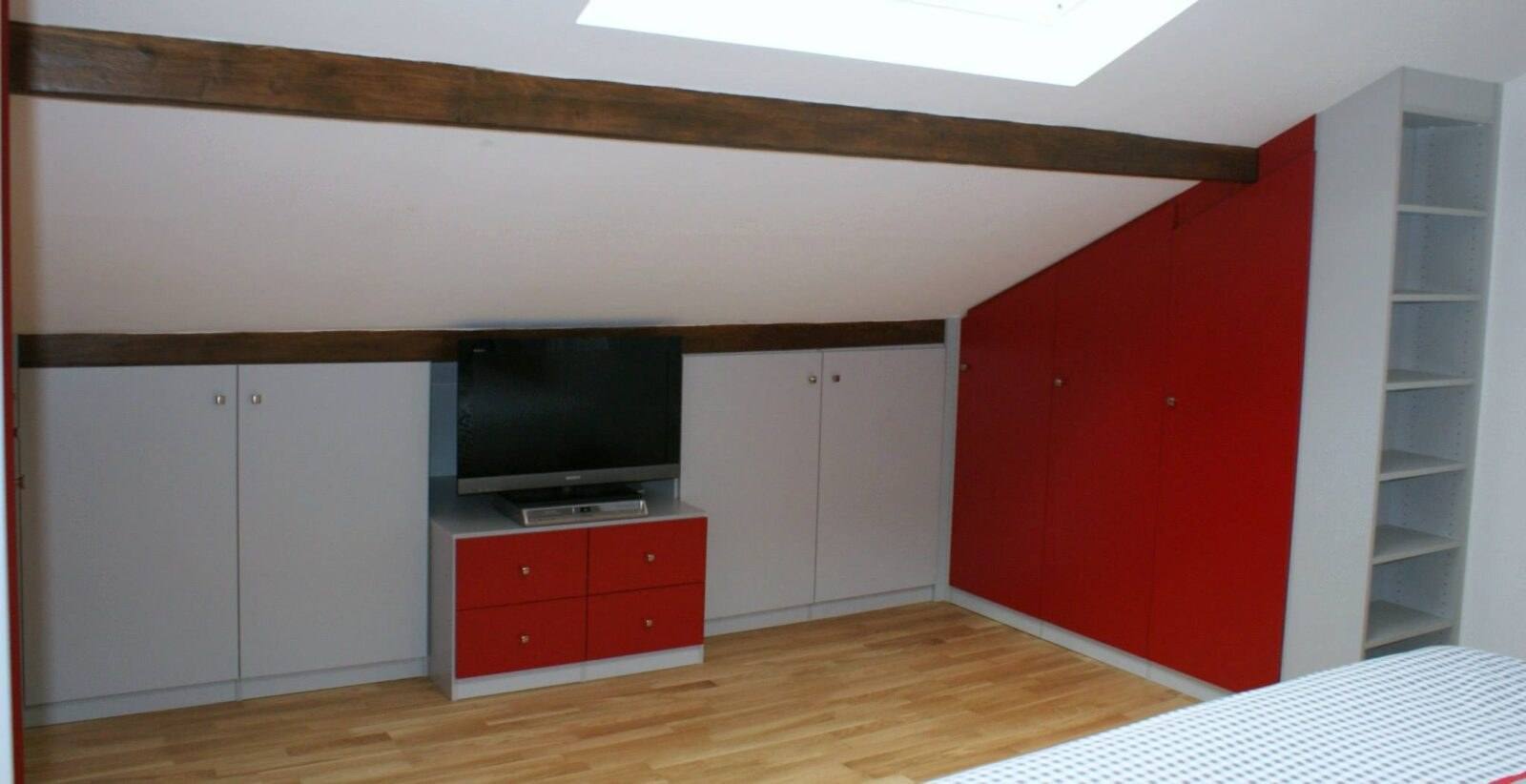 Combles aménagés avec placards blancs et rouges et meuble TV