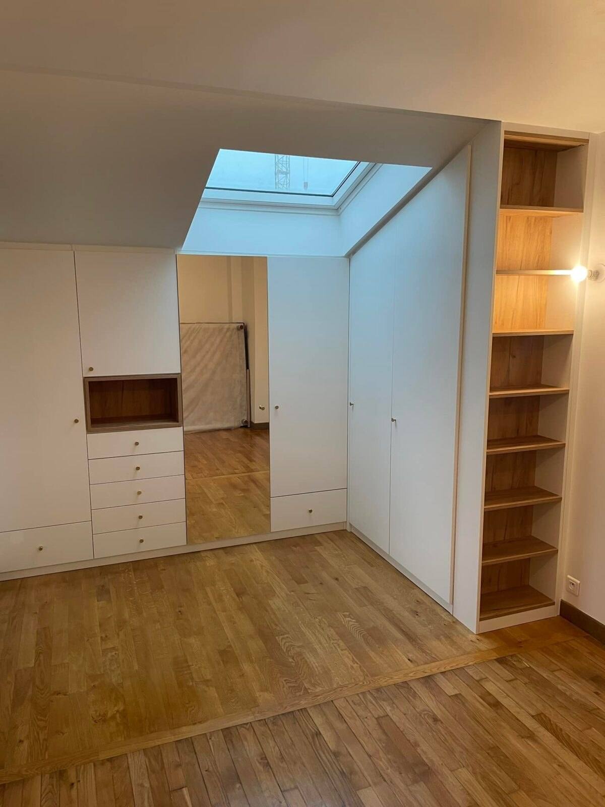 Dressing blanc sur mesure sous pente avec fenêtre de toit, tiroirs et colonne bois