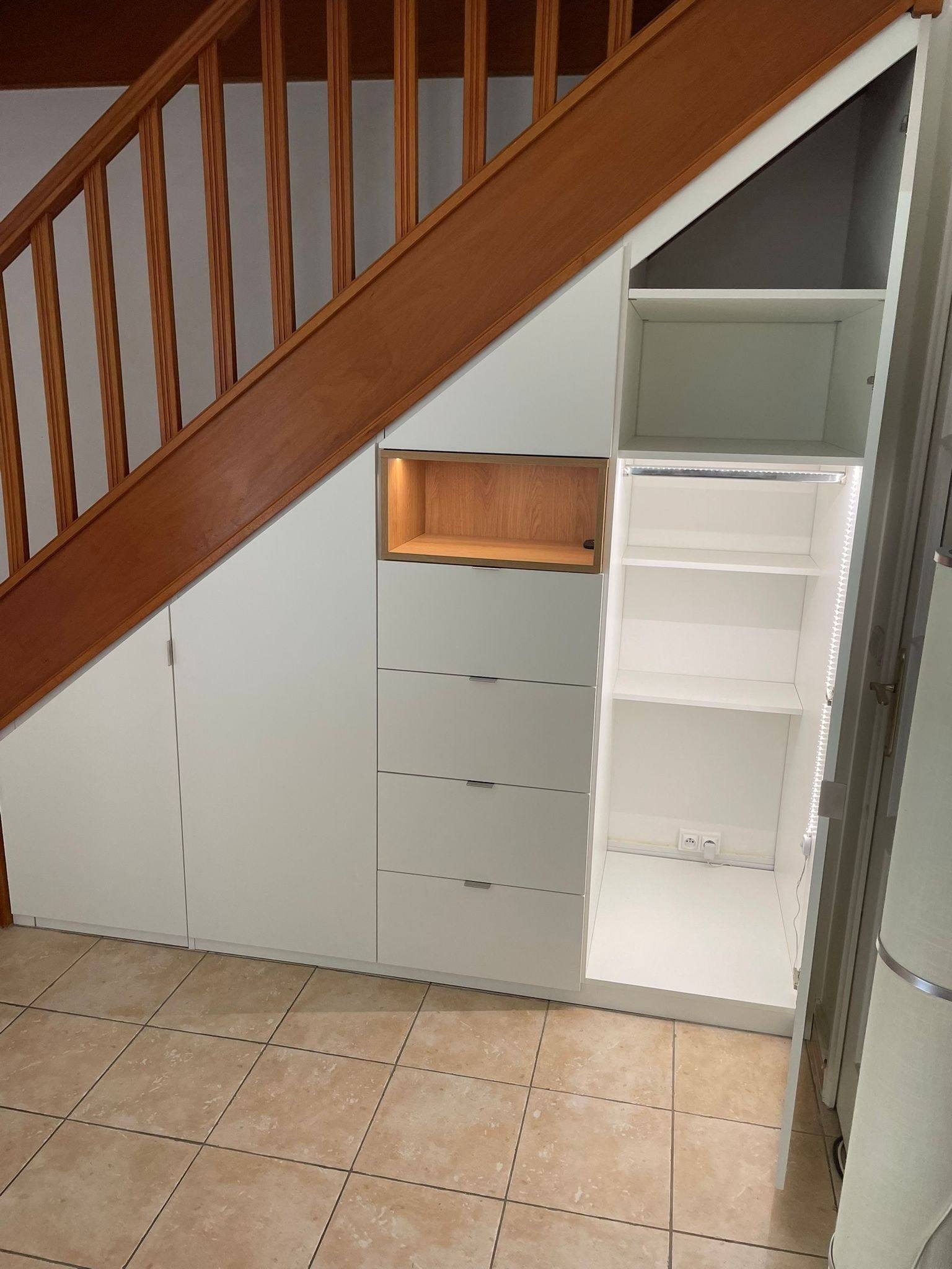 Meuble sous escalier blanc avec tiroirs, colonne d'étagères et niche bois éclairée, à Paris 10e